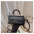 Detail of glossy black leather handbag featuring circular handle and silver hardware - Black