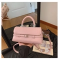 Detailed view of pink structured handbag with silver buckle and top handle in home setting - Pink