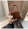 Detailed view of caramel brown leather bowling bag featuring a cute teddy bear charm - Coffee with Pendant