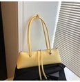 Close-up of vibrant yellow glossy leather shoulder bag with sleek metallic ring accents - Yellow