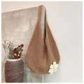 Detalle de bolso tote tejido con una flor de ganchillo sobre una pared texturizada - Caqui