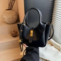 Sac seau rétro noir avec boucle dorée et breloque tissée dans un décor minimaliste - Noir avec pendentif