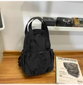 Detail of black waterproof nylon backpack with drawstring pocket on a wooden surface - Black