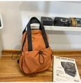 Close-up of the front drawstring pocket on a durable orange-brown nylon commuter backpack - Orange
