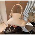 Makro-Detail der glänzenden cremefarbenen Muscheltasche mit silbernen Perlenbeschlägen - Cremeweiß