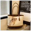 Dettaglio della borsa tote intrecciata crema con finiture in pelle marrone e fiocco in seta - Bianco Sporco