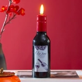 Close-up of LED wine bottle candle with realistic flame on decorative red background - Fixed Wick Style