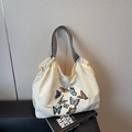 Beige canvas tote bag featuring colorful butterfly embroidery and woven handles - Off-white