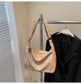 Detail view of large apricot shoulder bag with tassels on a metal rack with blazer - With Charm / Khaki