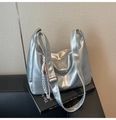 Detail of silver metallic hobo bag on books showing adjustable strap and texture - With Charm / Silver