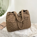 Elegante bolso tote acolchado marrón con costuras en V sobre fondo de encaje blanco - Caqui