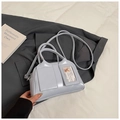 Light blue glossy leather crossbody bag with dual pockets and round handle on grey suit fabric - Blue Without Charm