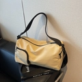 Beige canvas Boston bag with adjustable strap and side pocket detail on black sofa - Khaki