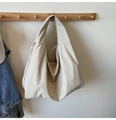 Close-up of beige oversized tote bag made of durable nylon hanging on a wooden hook - Off White