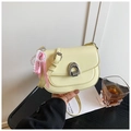Detail of a light yellow patent leather saddle bag with pearl and ribbon charms - With Charm / Yellow