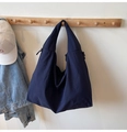 Detail of navy blue nylon tote bag hanging with casual denim jacket and baseball cap - Dark Blue