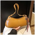 Close-up of ginger yellow crescent underarm bag with fringe and glossy PU leather finish - Brown with Pendant