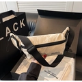 Gros plan d'un sac bandoulière en nylon crème avec fermeture éclair et logo noir - Blanc Cassé