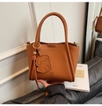 Close-up of brown pebbled leather handbag with PAN TOR logo and cute dog charm detail - Brown with Pendant