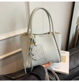 Detail of light grey lychee textured leather tote bag with branded charm and gold hardware - Blue with Charm