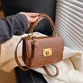 Brown leather crossbody bag with woven handle and gold clasp on minimalist decor - Brown