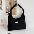 Minimalist black pleated hobo tote bag with a white rectangular brand logo patch - Black