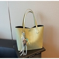 Detail of light green leather tote bag featuring a V-shaped cut and dog charm - Green