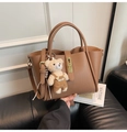 Close-up of brown pebbled leather tote bag with a golden buckle and bear charm - With Charm / Apricot