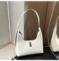 Detalle de bolso medialuna blanco brillante con hebilla metálica en base de madera - Blanco