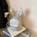 Mini light grey leather backpack with cute rabbit ears on a silver suitcase background - With Charm / Gray