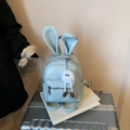 Light blue bunny ear backpack with fluffy charm on a silver suitcase for casual travel - With Charm / Blue