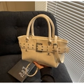 Detail of cream faux leather tote bag with silver eyelet belts on a corduroy chair - Off-white