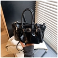 Primer plano detallado del bolso de cubo en cuero negro brillante con hebilla plateada - Negro