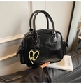 Details einer glänzenden schwarzen Boston-Tasche mit Seitentasche und Herzanhänger - Schwarz