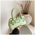 Close-up of mint green seashell handbag with lychee pattern and silver buckle hardware - Green