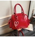 Detail of red glossy oil wax leather Boston bag with heart charm and side pockets - Red