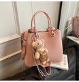 Détail du sac seau rose en cuir grainé avec charm ours et poignée nouée élégante - Rose avec pendentif