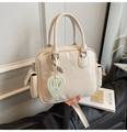 Detailaufnahme cremefarbene Boston-Tasche mit silbernen Beschlägen und Herzanhänger - Gebrochenes Weiß