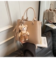 Détail du sac seau beige texture litchi avec poignée nouée et breloque ours en peluche - Khaki avec Pendentif