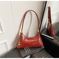 Gros plan sur un sac en cuir glacé brun-rouge avec garniture dorée et pendentif - Avec Pendentif / Rouge