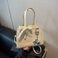 Bolso Boston de charol crema con lazo de encaje y colgante de perro de globo metálico - Blanco Roto