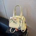 Bolso Boston de charol amarillo pálido con lazo de encaje crema y colgante plateado - Amarillo