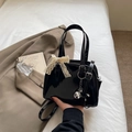 Bolso Boston de charol negro con lazo de encaje blanco y colgante de metal plateado - Negro