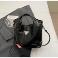 Detailed close-up of glossy black faux leather tote with metallic triangle emblem and texture - One Size / Black