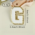 Detailed view of white chenille letter G patch with gold glitter edge and 8cm dimensions - Letter G / White / Hot Melt Adhesive