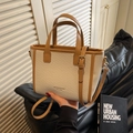 Beige gewebte Eimertasche mit braunem Lederbesatz und praktischem Umhängeriemen - Webdesign / Cremeweiß