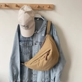 Khaki crescent crossbody chest bag with woven zipper pull over a denim jacket - Khaki