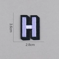 Détail de l'écusson brodé lettre H violet et noir avec mesure de hauteur de 3,6 cm - Lettre H