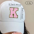 Detail of pink chenille letter K patch with gold glitter edge on a white baseball cap - Letter K / Pink / Hot Melt Adhesive