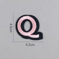 Détail d'un écusson brodé lettre Q rose avec bordure noire et dimensions de 4,5 cm - Lettre Q